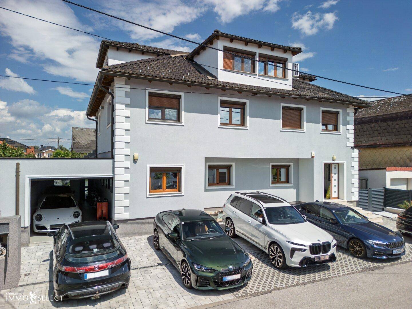 Moderne Hausfassade mit mehreren Parkplätzen und integrierter Garage, in einem gepflegten Zustand.