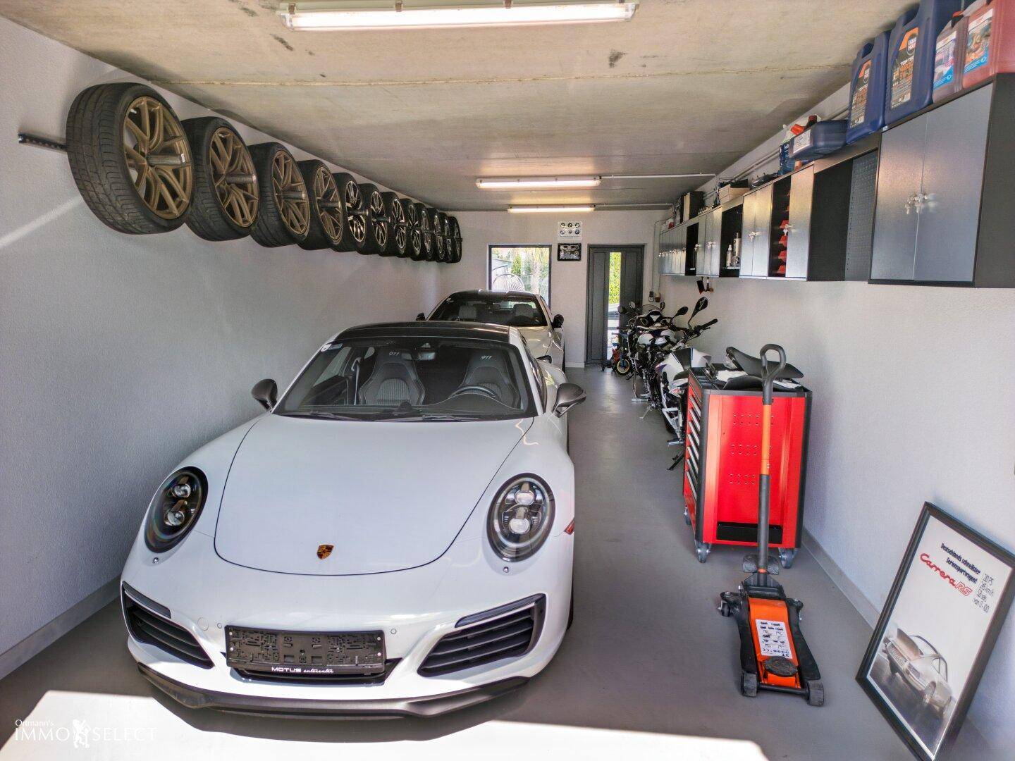 Geräumige Garage mit Platz für mehrere Fahrzeuge und Reifenlagerung, gut organisiert und beleuchtet.