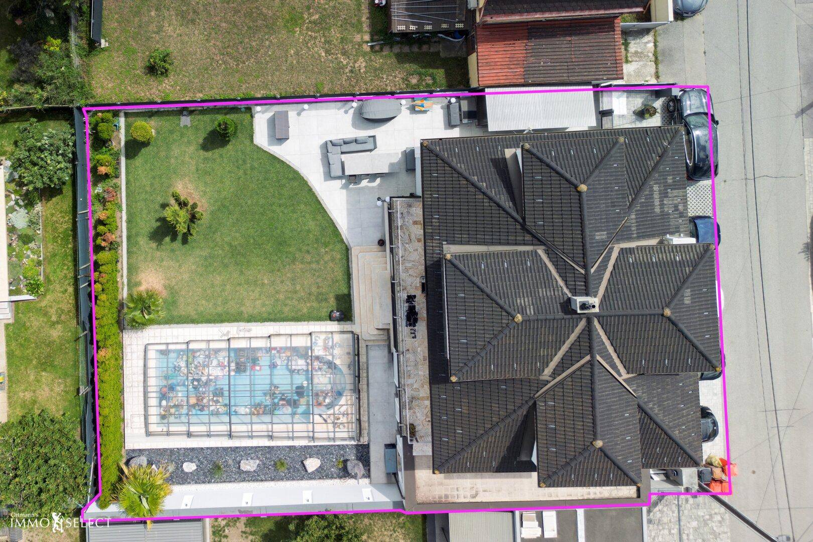 Draufsicht des Grundstücks mit Haus, Garten, Pool und klar definierten Grenzen, umgeben von Grünflächen.