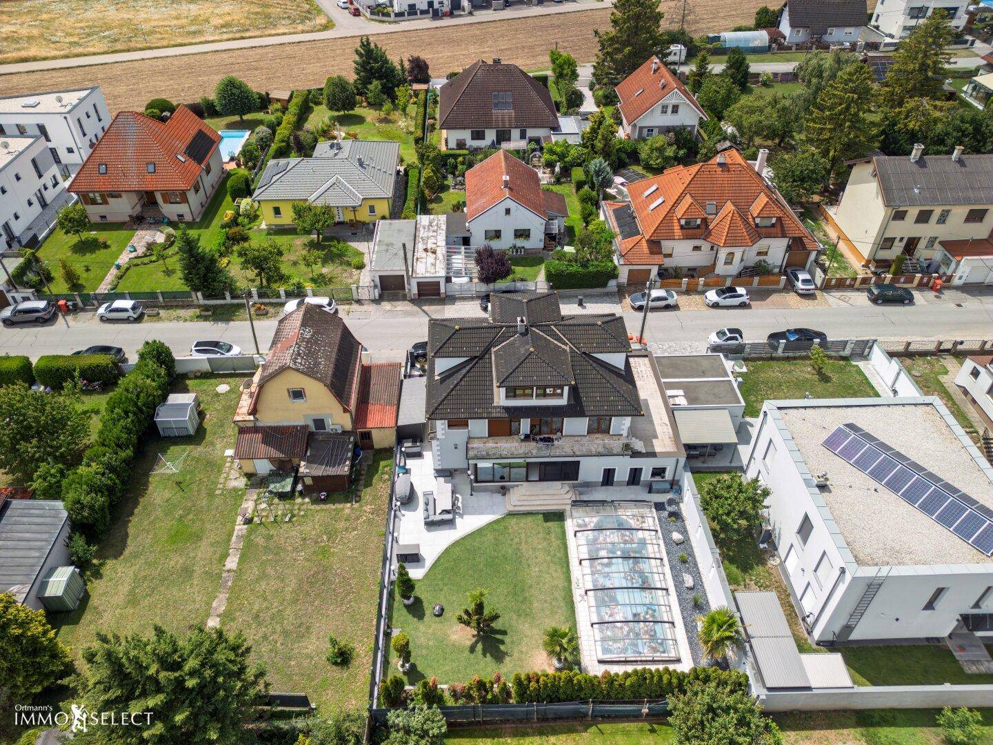 Panoramablick aus der Luft auf das Wohngebiet mit verschiedenen Häusern und Gärten, umgeben von Natur.