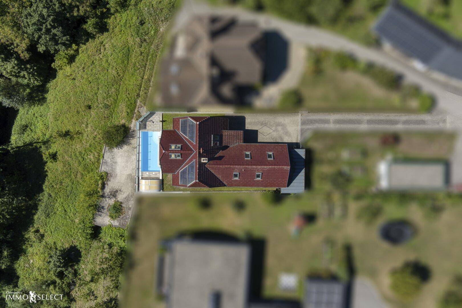 Draufsicht auf das Anwesen mit Haus, Pool, Photovoltaikanlage und umliegender Natur.