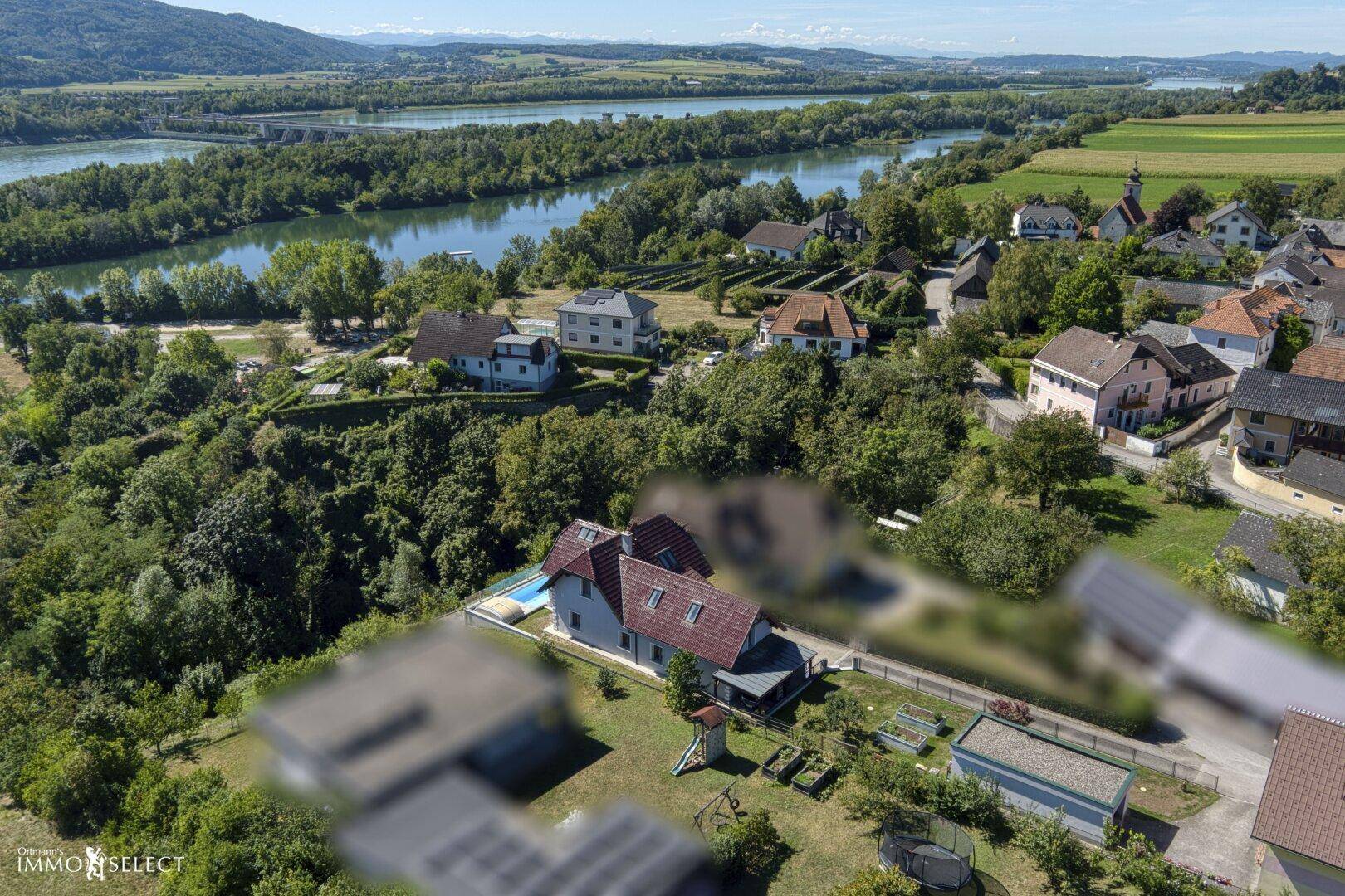 Weitläufige Luftaufnahme des Anwesens mit Fluss, Wäldern und umliegender Bebauung.