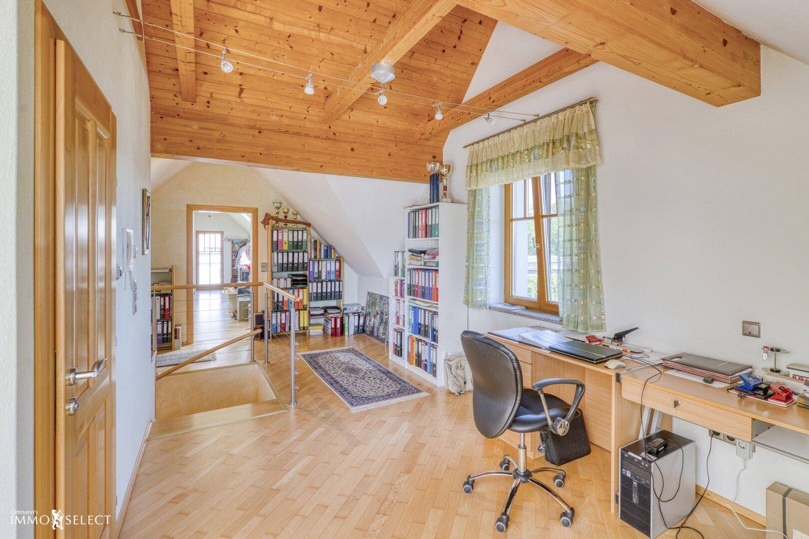 Geräumiges Dachgeschoss-Büro mit Holzbalken, Parkettboden und viel natürlichem Licht.