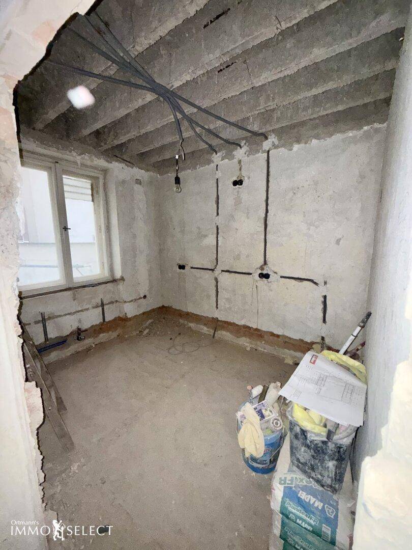 Kleiner Raum in Renovierung mit freiliegenden Elektroleitungen und einem Fenster.