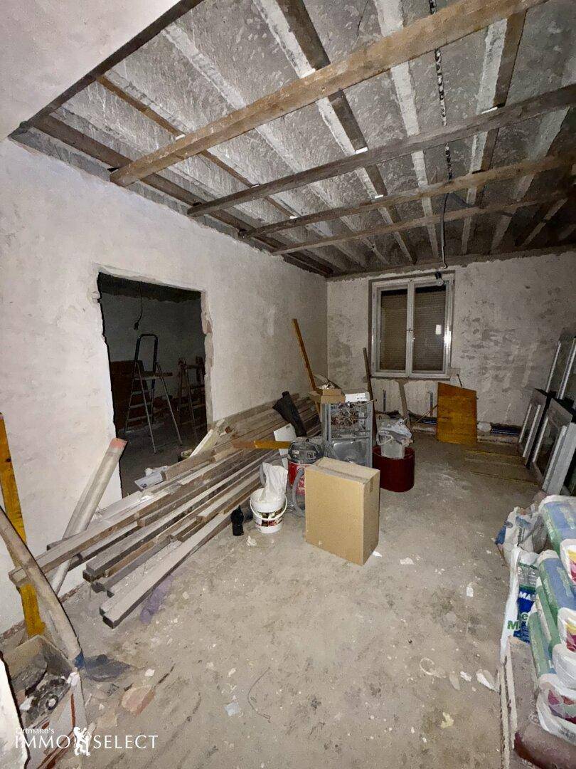 Großer Raum in Renovierung mit Baumaterialien und freiliegender Deckenkonstruktion.