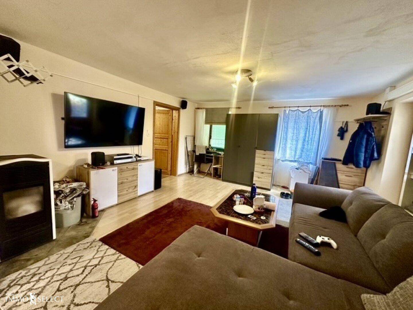 Wohnzimmer mit großem Fernseher, modernem Holzofen und hellem Holzboden.