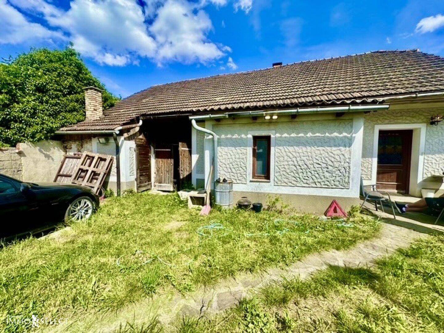 Seitenansicht des Hauses mit gepflegter Fassade, Ziegeldach und einem kleinen Vorgartenbereich.