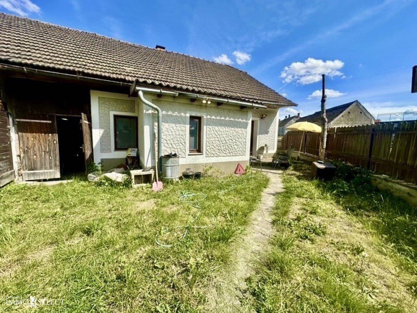 Ansicht des Hauses von der Seite mit einem grasbewachsenen Weg und einem Holzzaun.