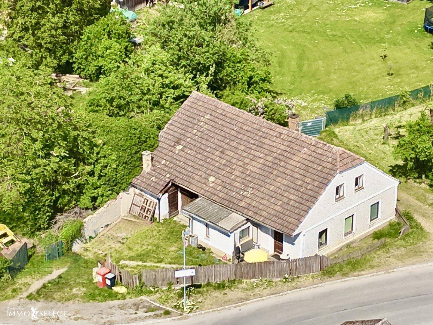 Luftaufnahme des Hauses mit Ziegeldach, umgeben von grüner Landschaft und Bäumen.