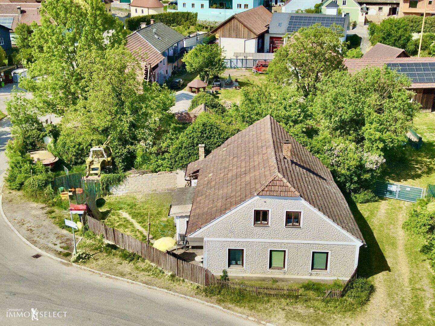 Weitläufige Luftaufnahme des Hauses in einer ländlichen Siedlung mit umliegenden Gärten und Feldern.