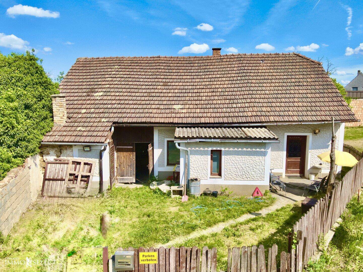 Ansicht des Hauses von der Straße mit Holzzaun und einem kleinen Vorgartenbereich.