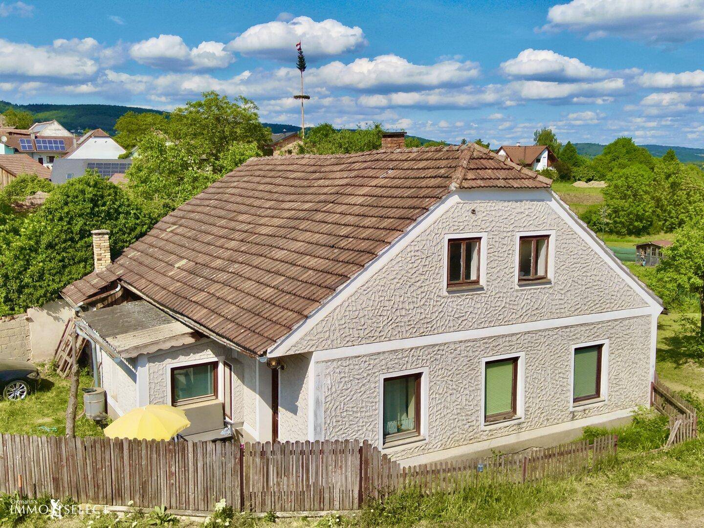 Charmantes Einfamilienhaus mit Satteldach und strukturierter Fassade in ländlicher Umgebung unter blauem Himmel.