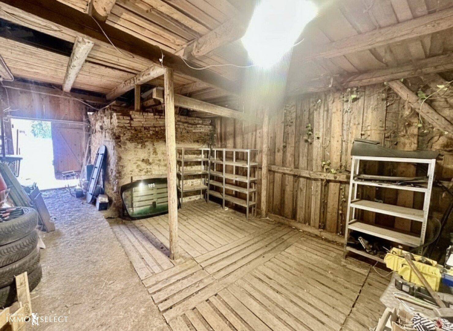 Großer rustikaler Raum mit Holzwänden, Ziegelmauerwerk und Metallregalen für Lagerzwecke.