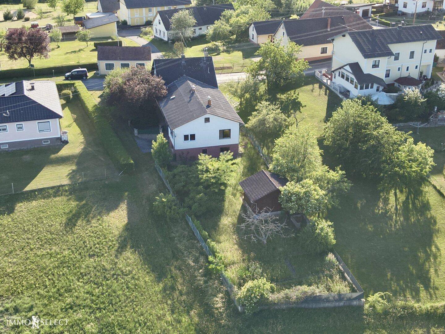 Luftaufnahme des Anwesens mit Haus und Garten, eingebettet in die grüne Landschaft mit angrenzender Straße.