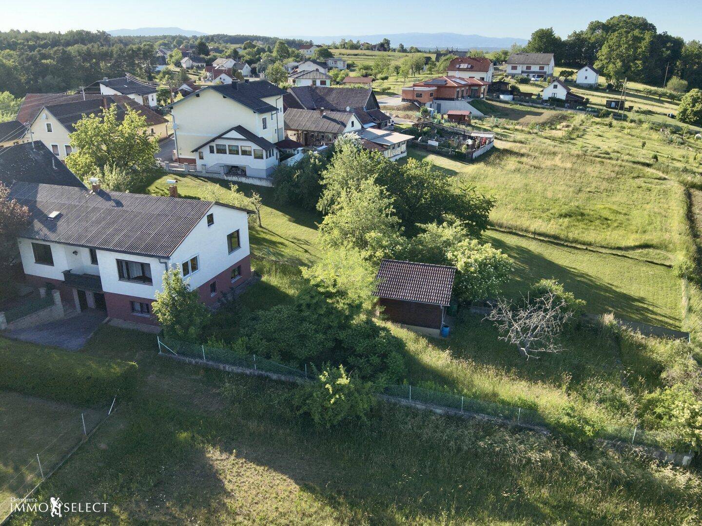 Luftaufnahme des Anwesens mit umliegenden Häusern und weitem Blick auf die sanften Hügel der Umgebung.