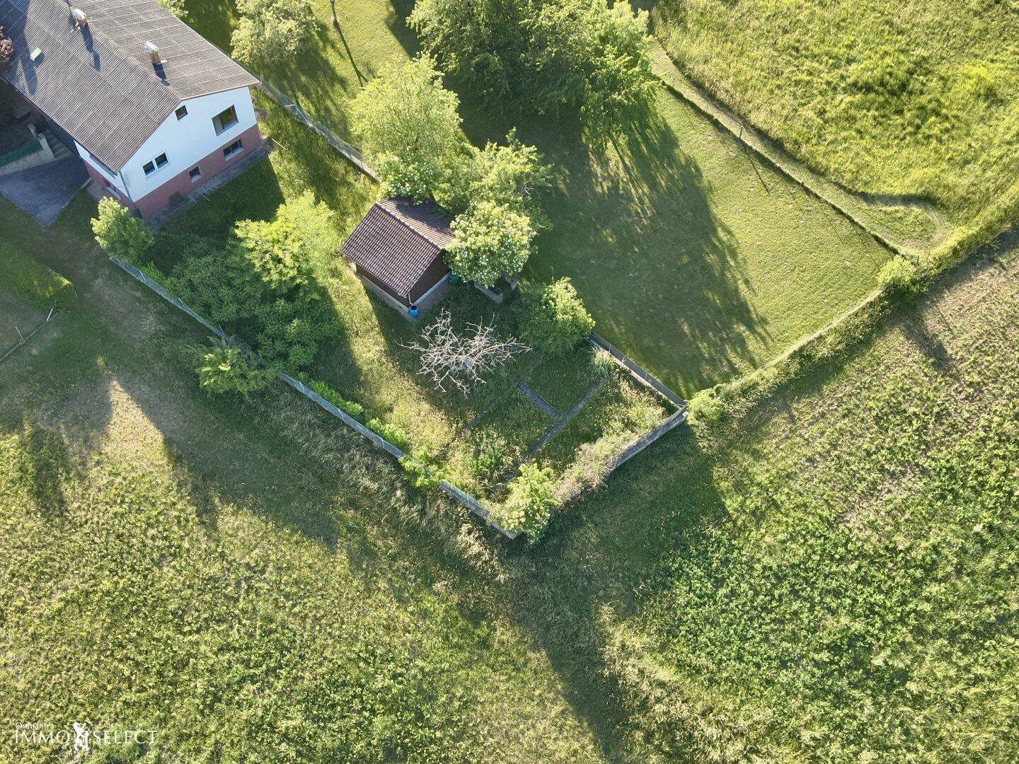 Vogelperspektive eines Gartengrundstücks mit einem kleinen Schuppen und umgebenden Grünflächen.