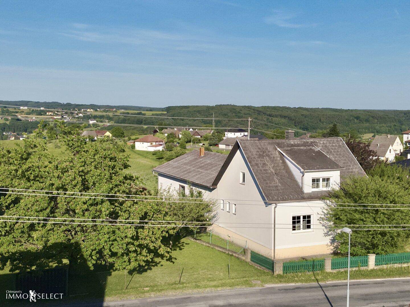 Weitwinkelaufnahme eines Wohnhauses in einer ländlichen Umgebung mit weitem Blick über grüne Felder.