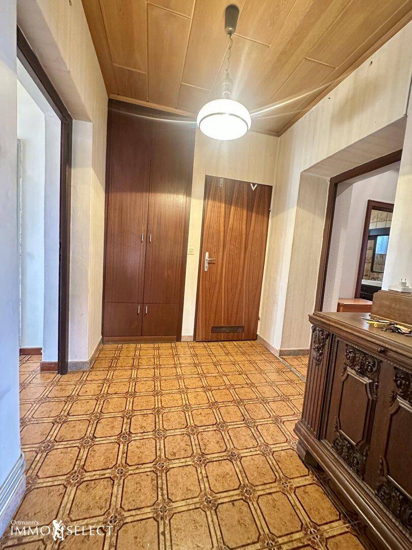 Geräumiger Flur mit gemustertem Fliesenboden, Holzdecke und einem antiken Sideboard.