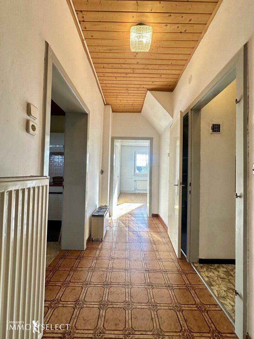 Heller Flur mit gemustertem Fliesenboden, Holzdecke und Zugang zu weiteren Räumen.