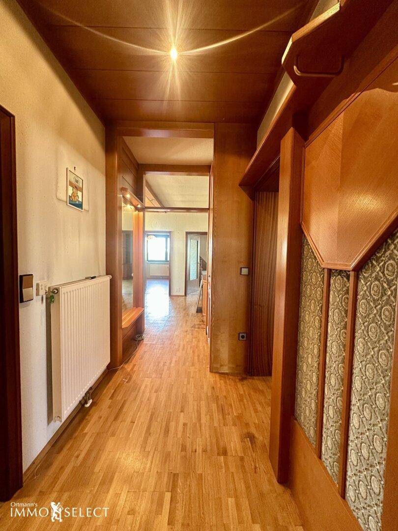 Langer Flur mit Holzparkettboden, Holzvertäfelung an der Decke und Zugang zu weiteren Räumen.