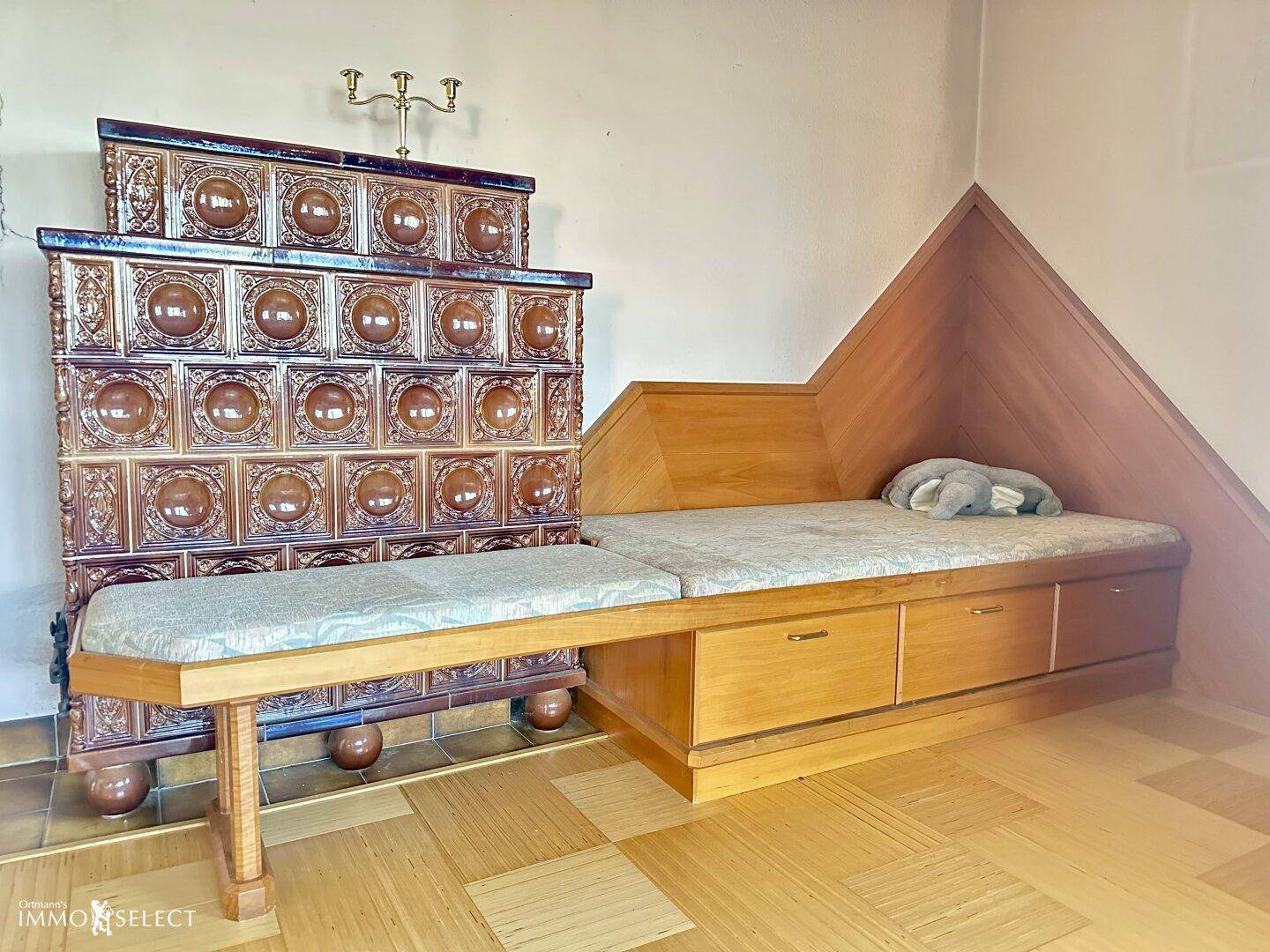 Detailansicht eines traditionellen Kachelofens mit integrierter Sitzbank und Holzvertäfelung.