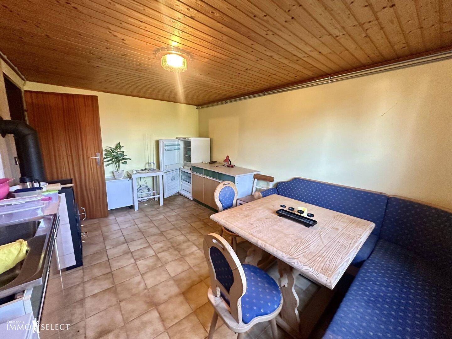Küche mit Essbereich, Holzofen und Kühlschrank, bereit für die Zubereitung von Mahlzeiten.