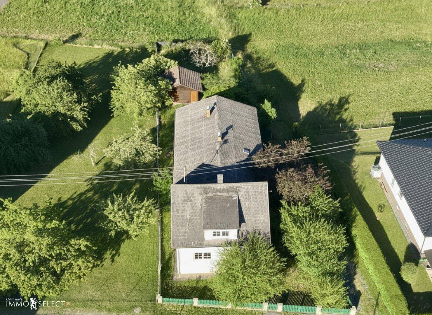 Direkte Draufsicht auf ein Wohnhaus mit Satteldach und angrenzendem Gartenbereich in ländlicher Lage.