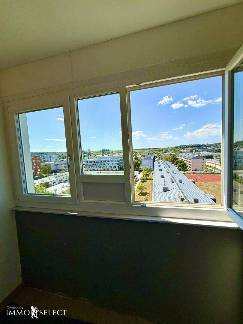 Kleiner Balkon mit weitem Blick über die umliegende Wohngegend und viel Grün.
