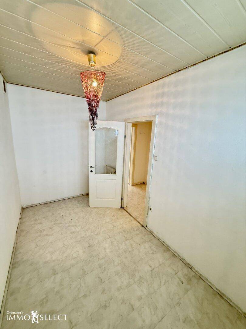 Kleiner Raum mit PVC-Boden, Holzdecke und einer auffälligen Hängelampe.