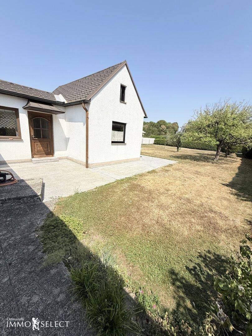 Seitlicher Blick auf das Haus mit einer kleinen Terrasse und dem weitläufigen Gartenbereich.