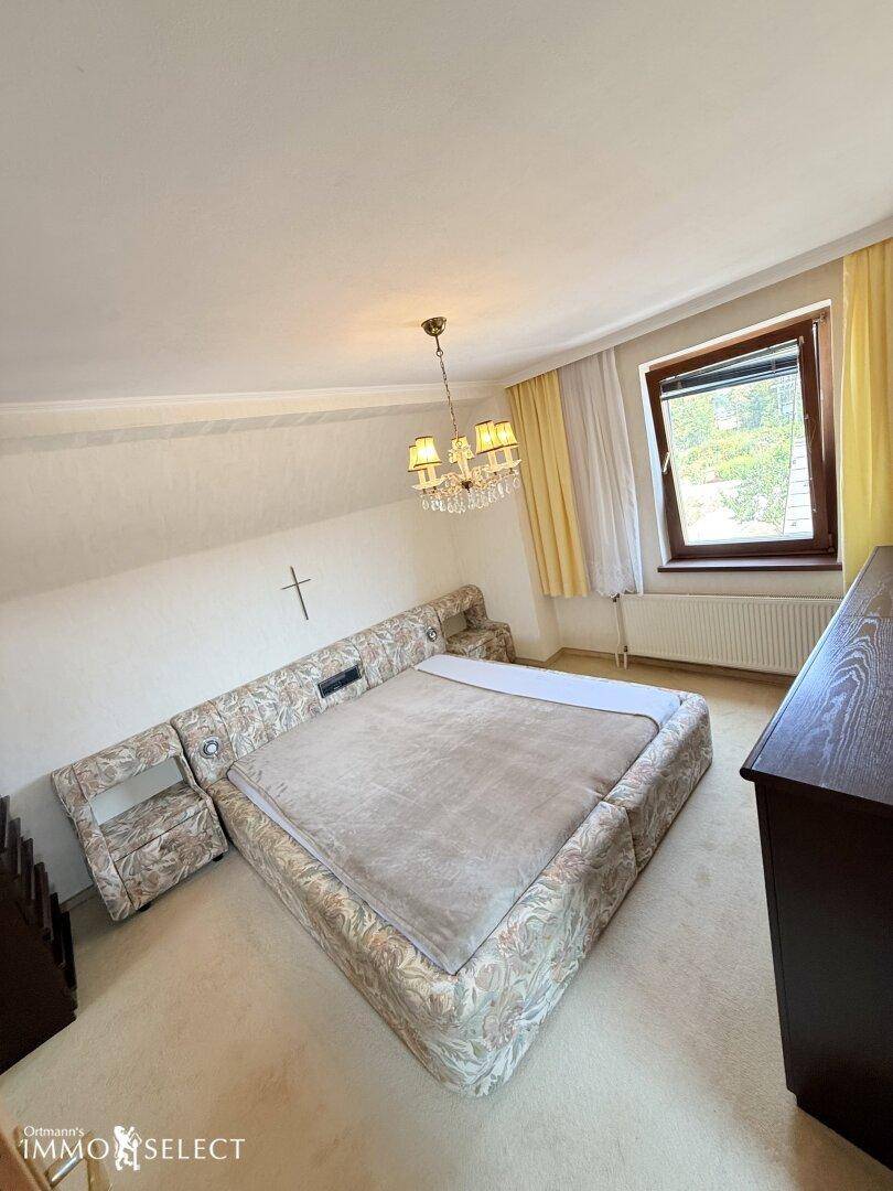 Gemütliches Schlafzimmer im Dachgeschoss mit großem Bett, Teppichboden und schrägen Decken.