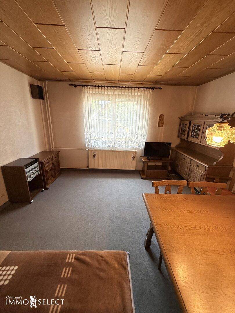 Traditioneller Wohn- und Essbereich mit Teppichboden, Holzdecke und klassischem Mobiliar.
