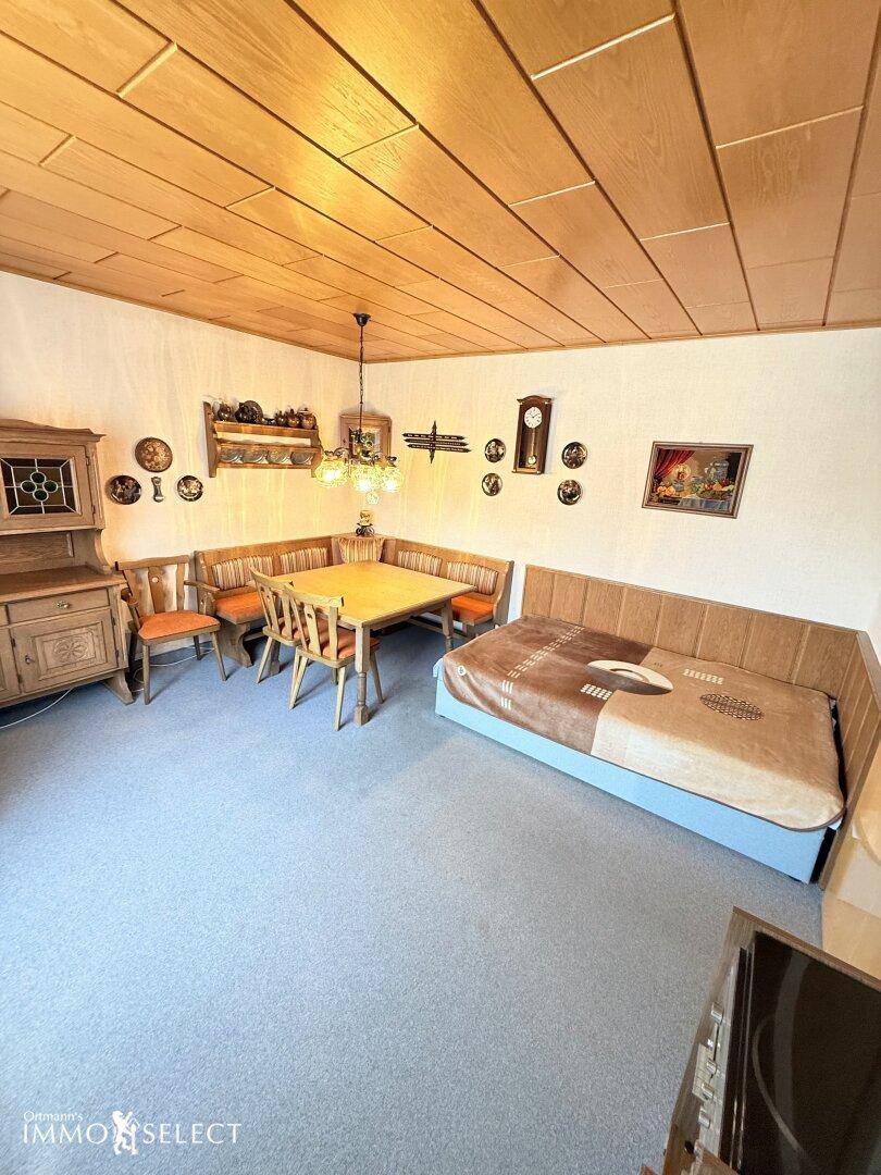 Gemütlicher Wohn- und Essbereich mit Holzdecke, Teppichboden und traditionellen Möbeln, inklusive Tagesbett.