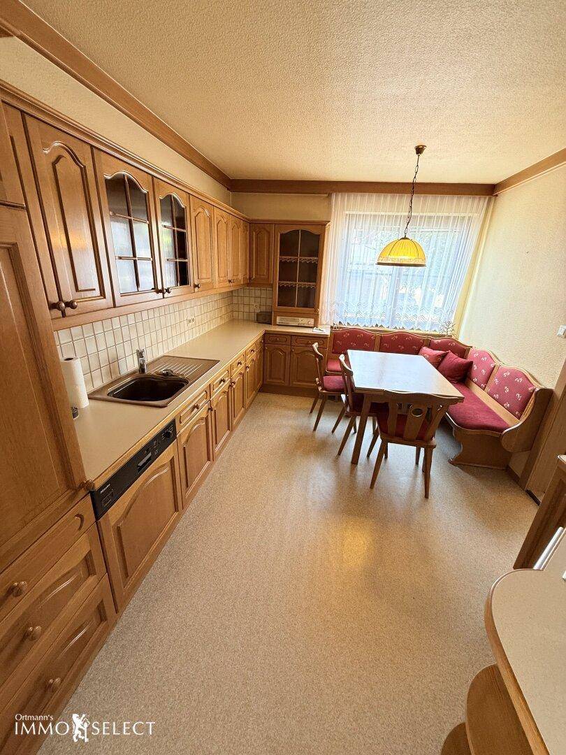 Traditionelle Küche mit Holzschränken, hellem Arbeitsbereich und einer gemütlichen Essecke am Fenster.