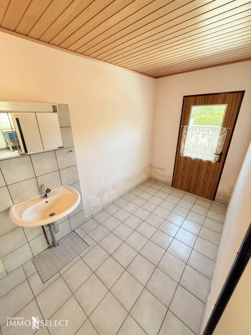 Gäste-WC mit Waschbecken, Spiegelschrank und hellem Fliesenboden, ideal für Besucher.
