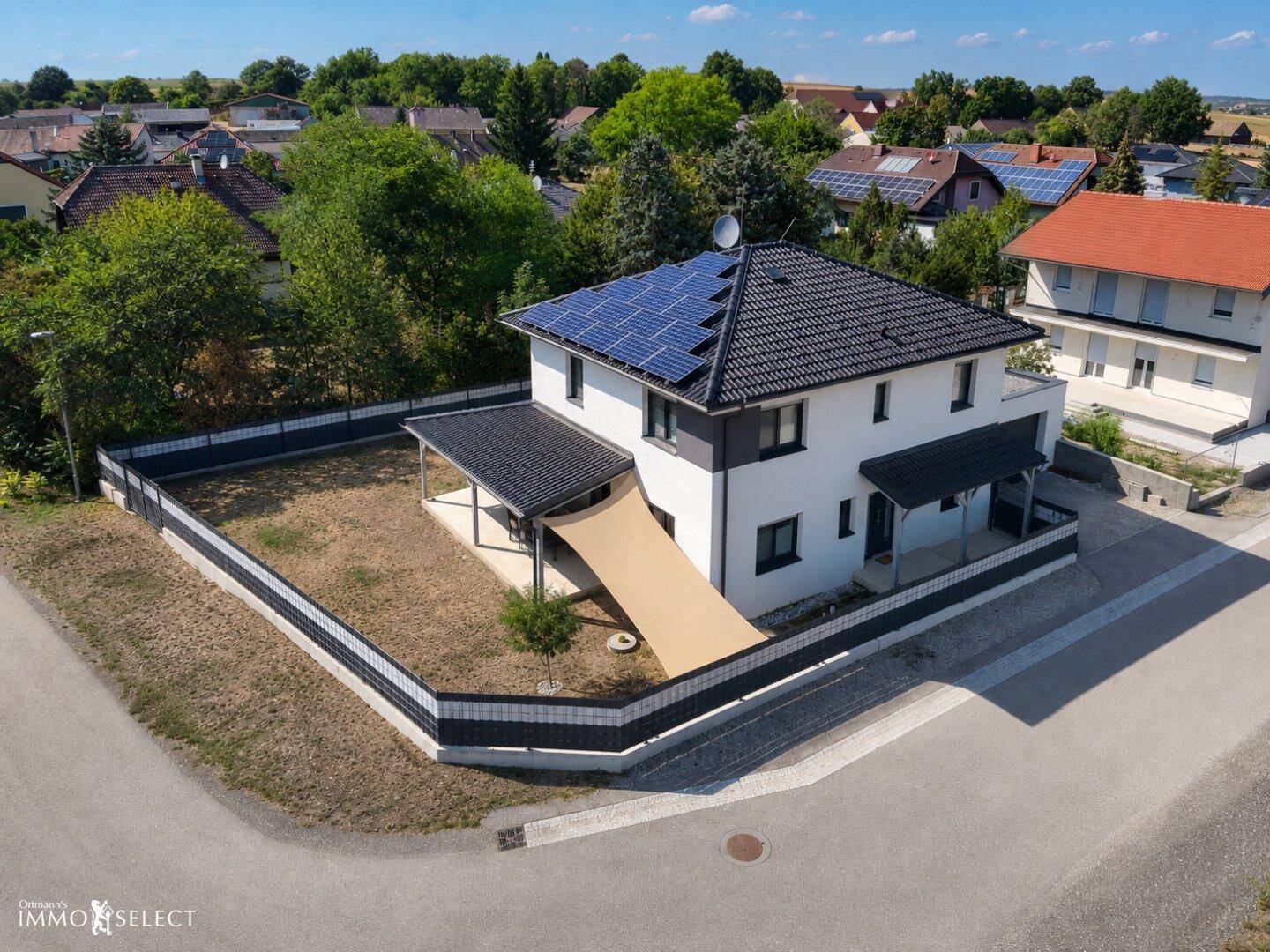 Luftaufnahme eines Einfamilienhauses mit Photovoltaikanlage und großem Gartenbereich.