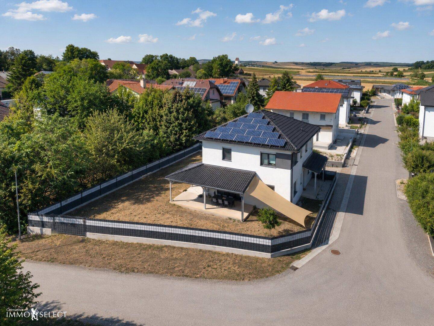 Weitläufige Ansicht eines modernen Hauses mit Solaranlage und großem Grundstück.