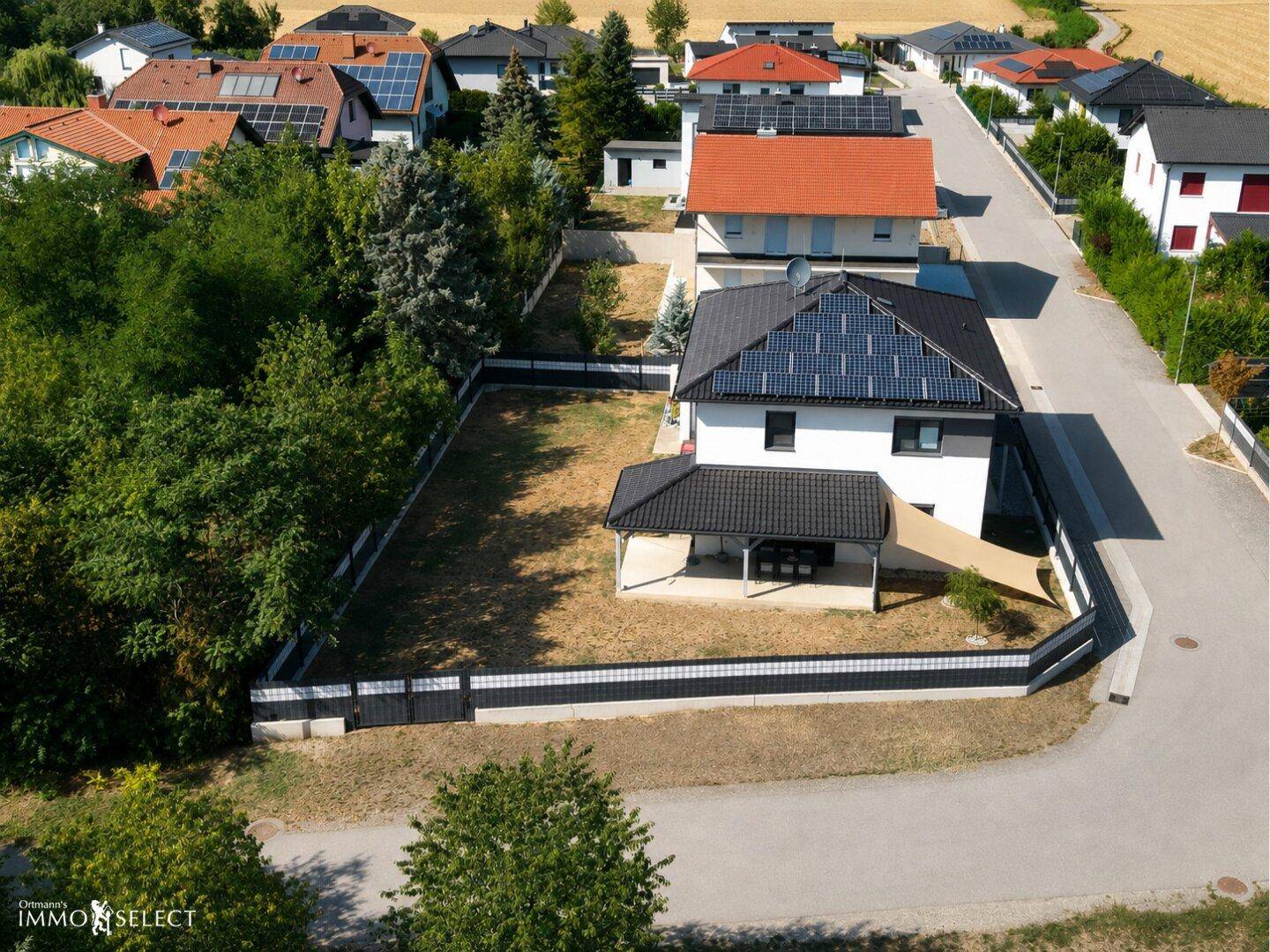 Luftaufnahme des Hauses mit Photovoltaikanlage, Garten und umgebender Landschaft.