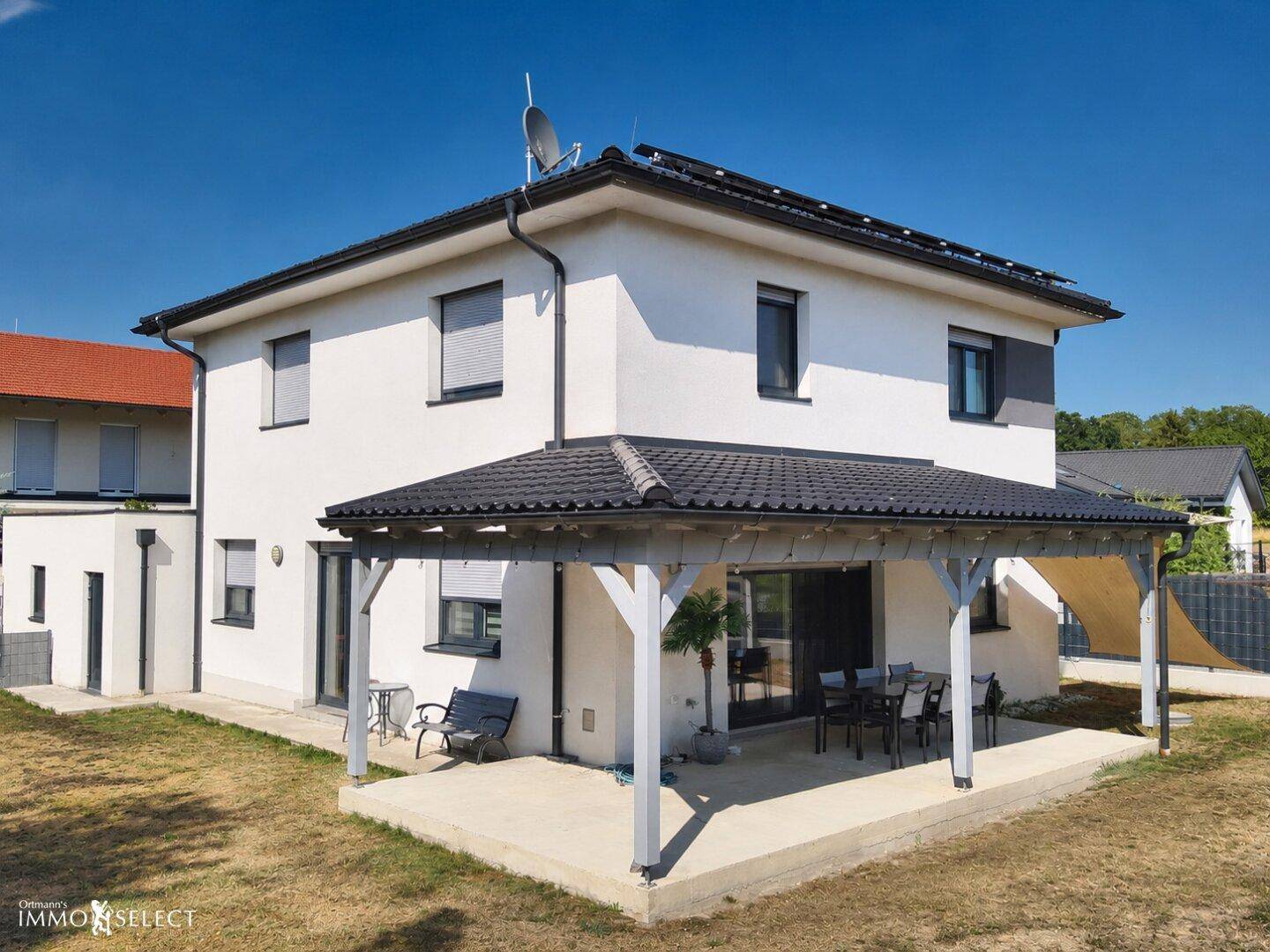 Seitenansicht des Hauses mit überdachter Terrasse und angrenzendem Gartenbereich.