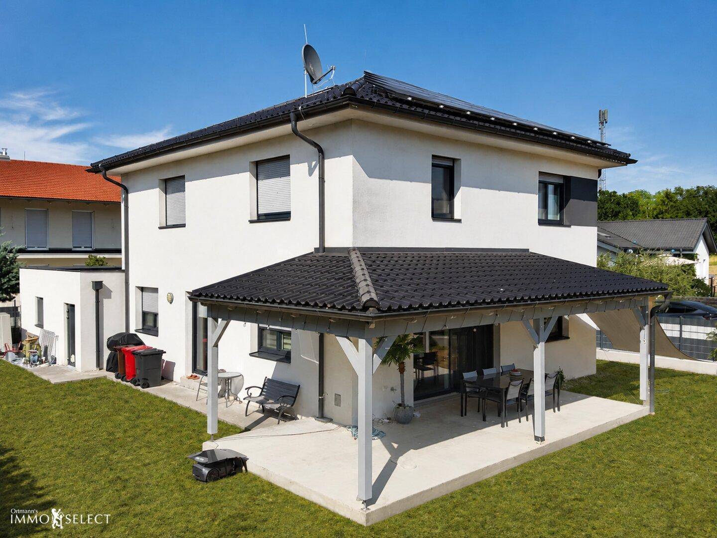 Seitenansicht des Hauses mit überdachter Terrasse, Garten und einem Grillbereich.