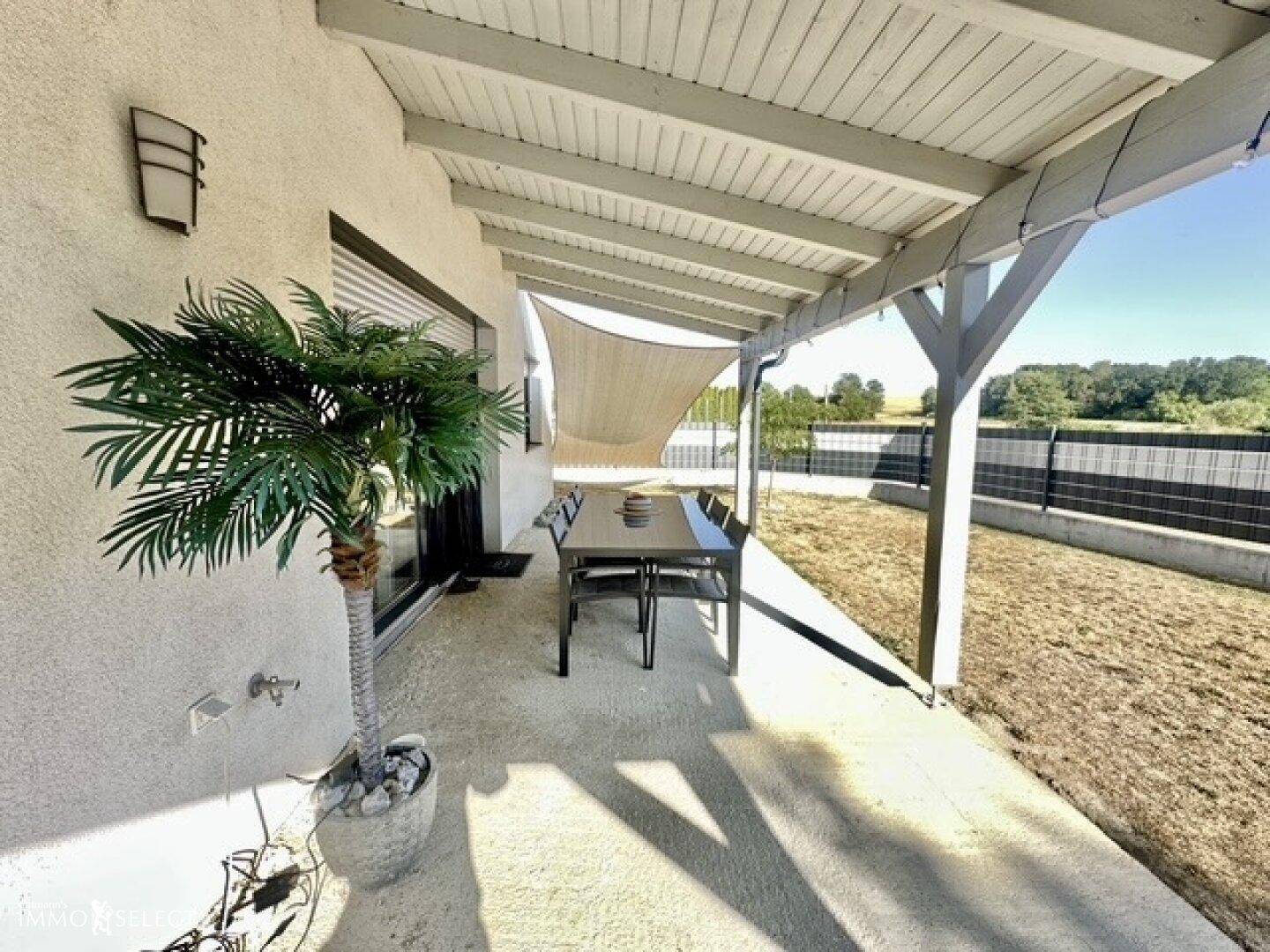 Überdachte Terrasse mit Esstisch und Blick auf den Garten, ideal für Mahlzeiten im Freien.