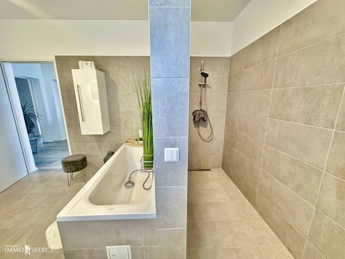 Modernes Badezimmer mit begehbarer Dusche und Badewanne, ausgestattet mit hellgrauen Fliesen.