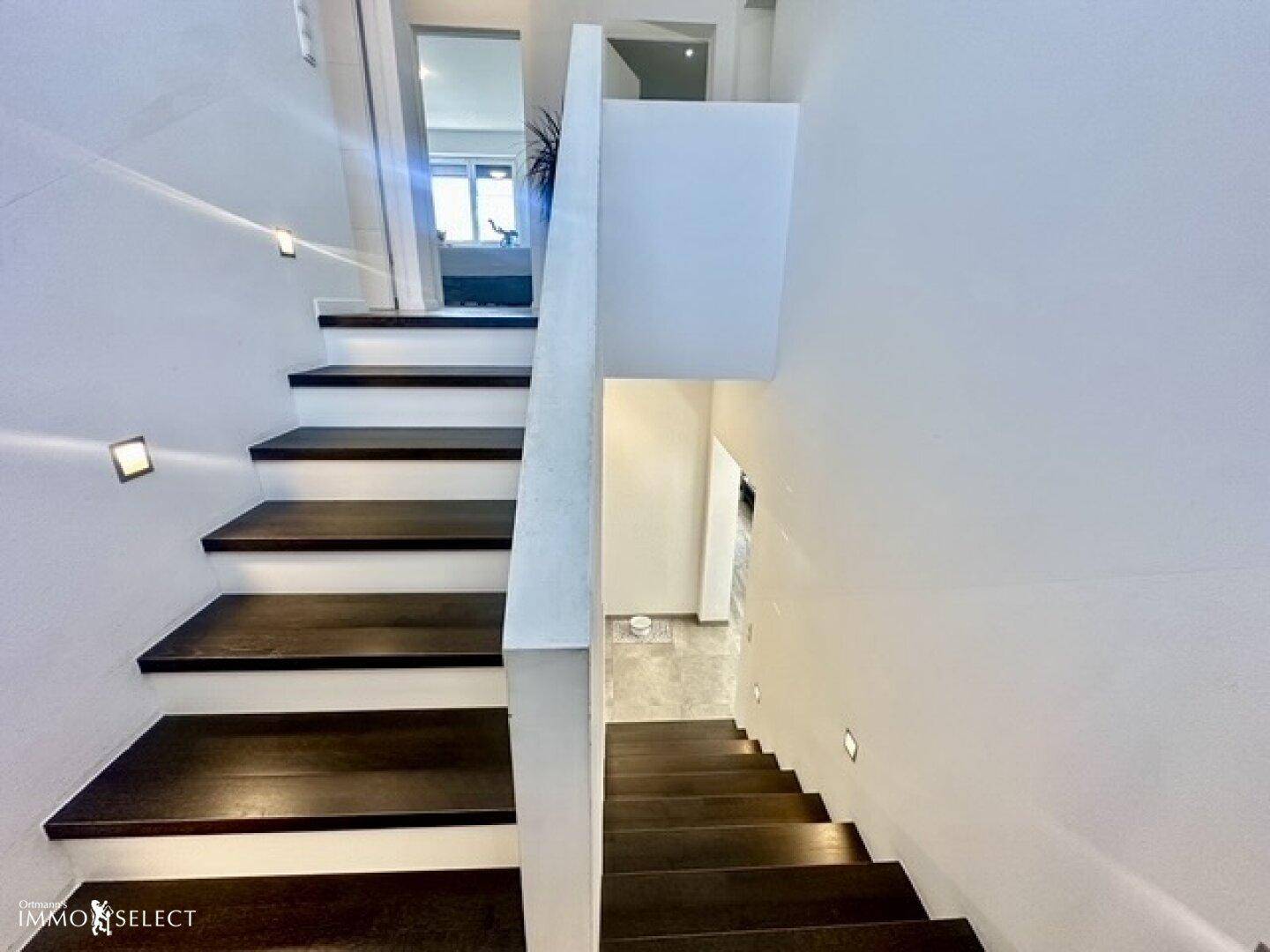Moderne Treppe mit dunklen Holzstufen und integrierter Beleuchtung.