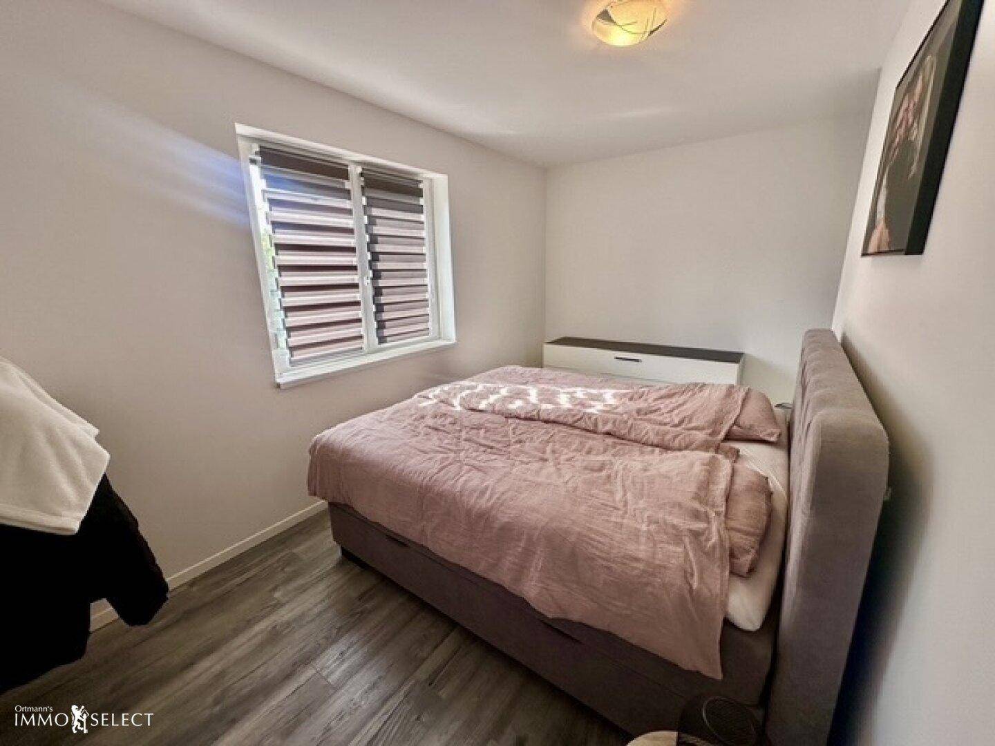 Gemütliches Schlafzimmer mit einem Bett und einem Fenster, ausgestattet mit Laminatboden.