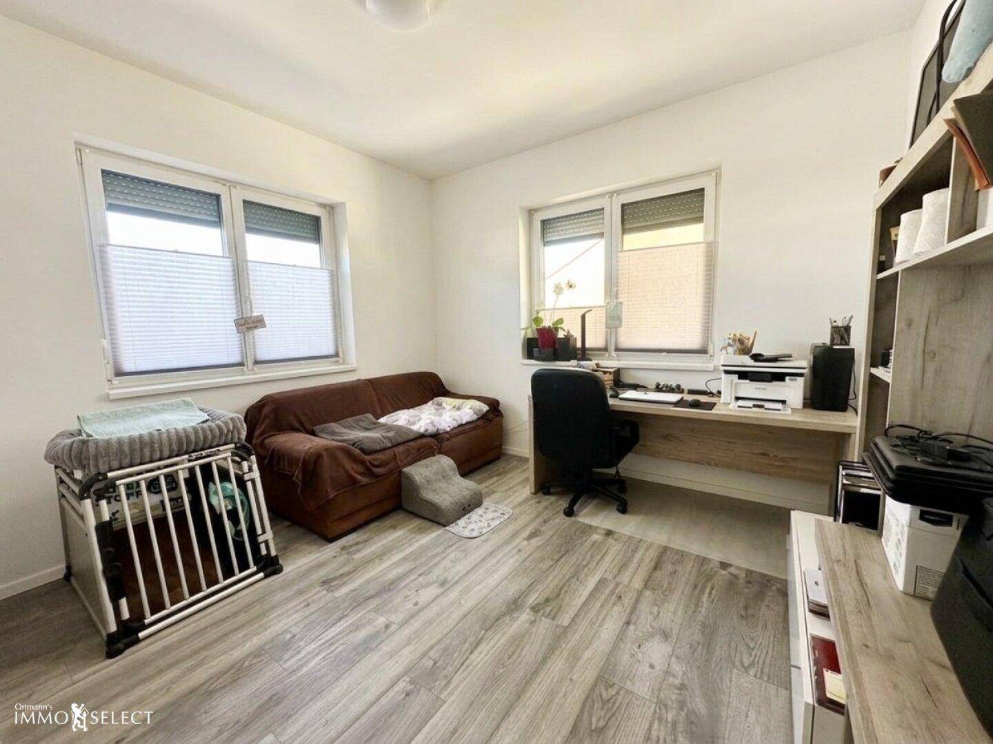 Funktionales Arbeitszimmer mit Schreibtisch, Sofa und zwei Fenstern, ideal für Home-Office.