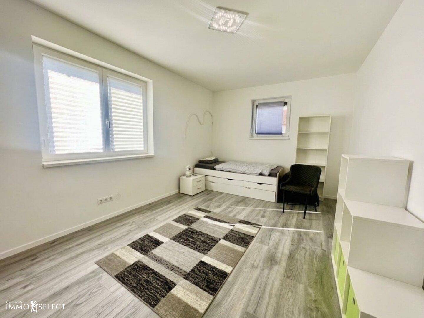 Helles Kinder- oder Gästezimmer mit Einzelbett, Regalen und modernem Laminatboden.