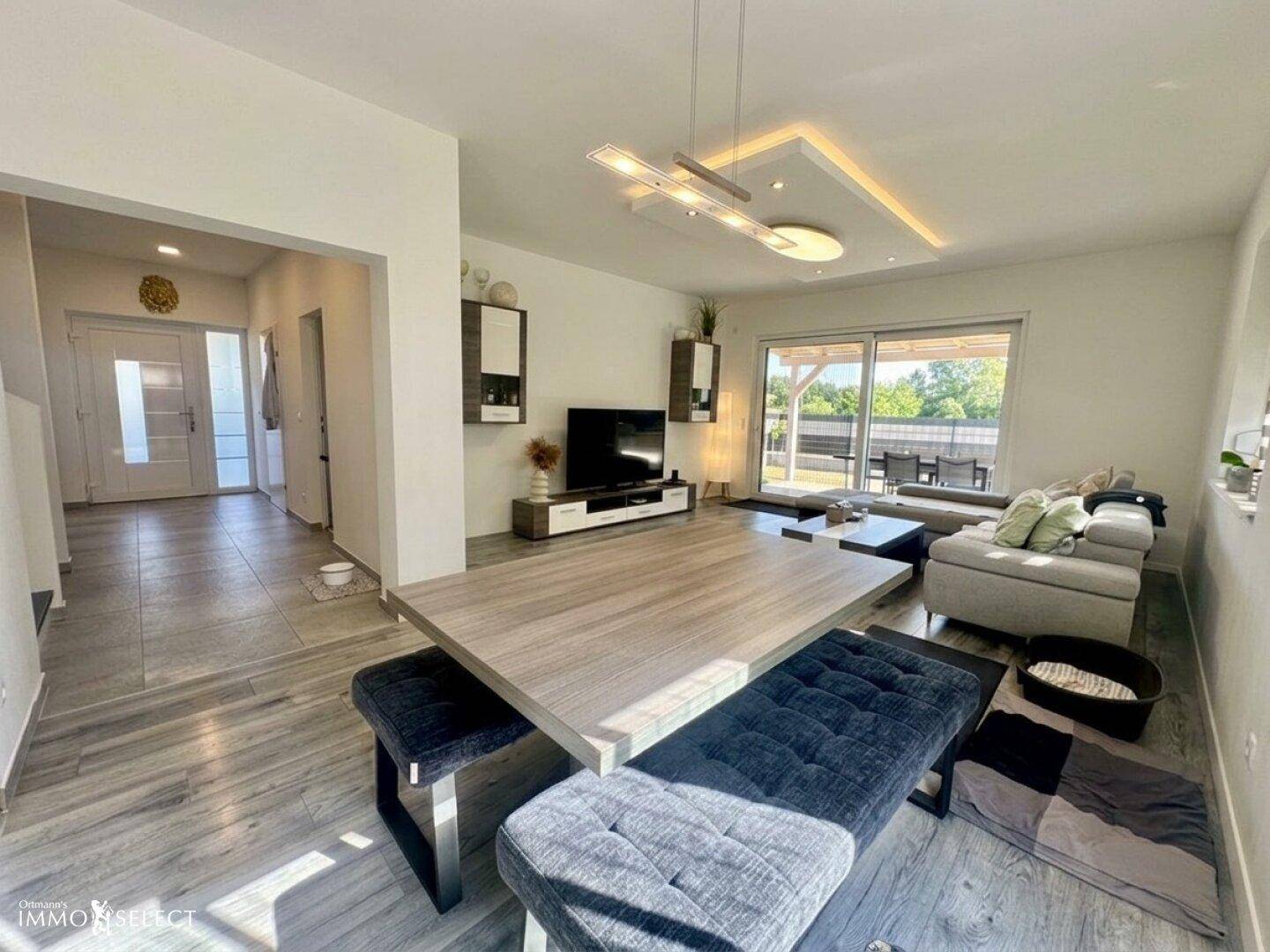 Offener Wohn- und Essbereich mit großem Esstisch, bequemer Couch und Zugang zur Terrasse.