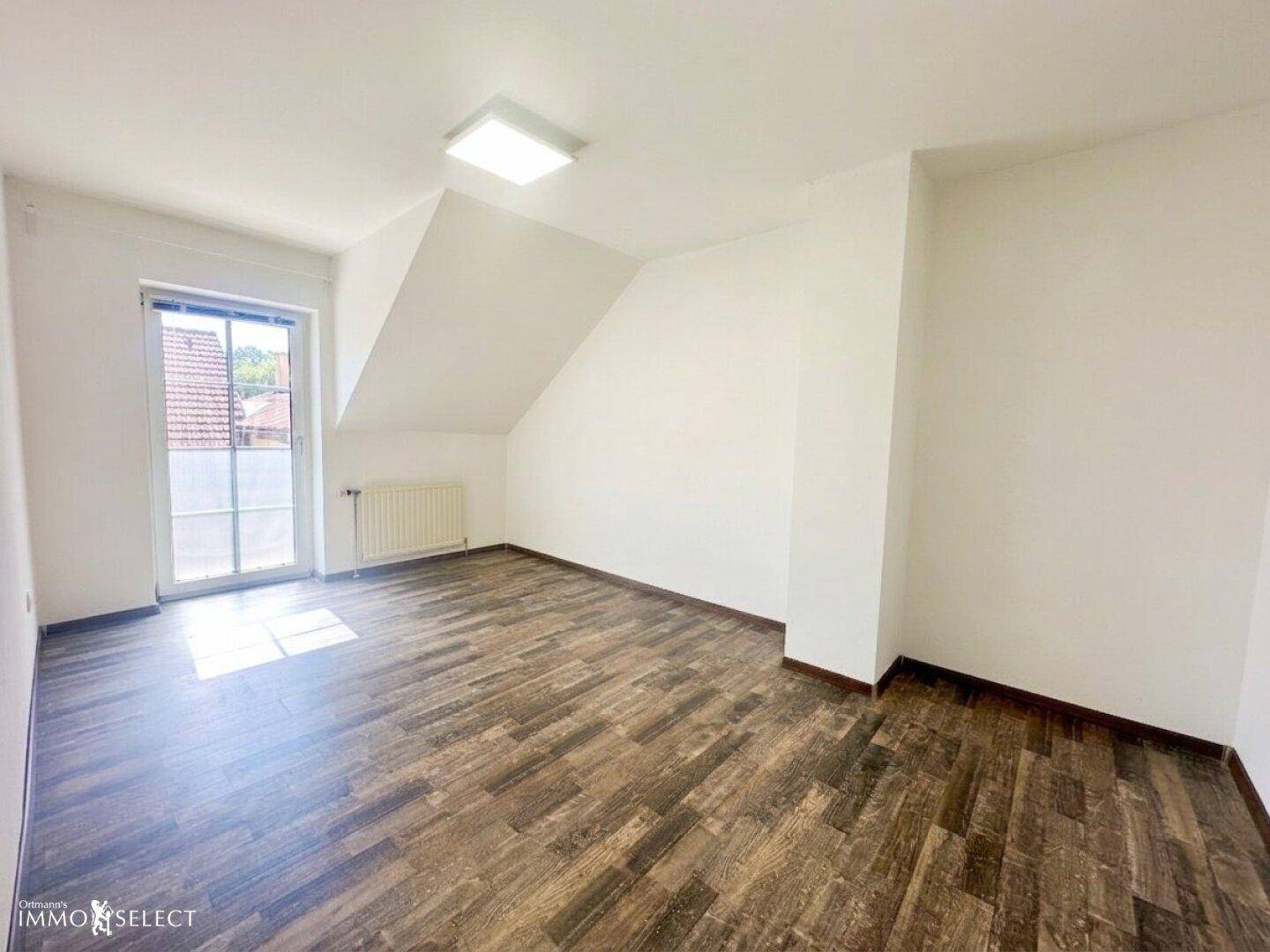Helles Dachgeschosszimmer mit modernem Laminatboden und französischem Balkon.