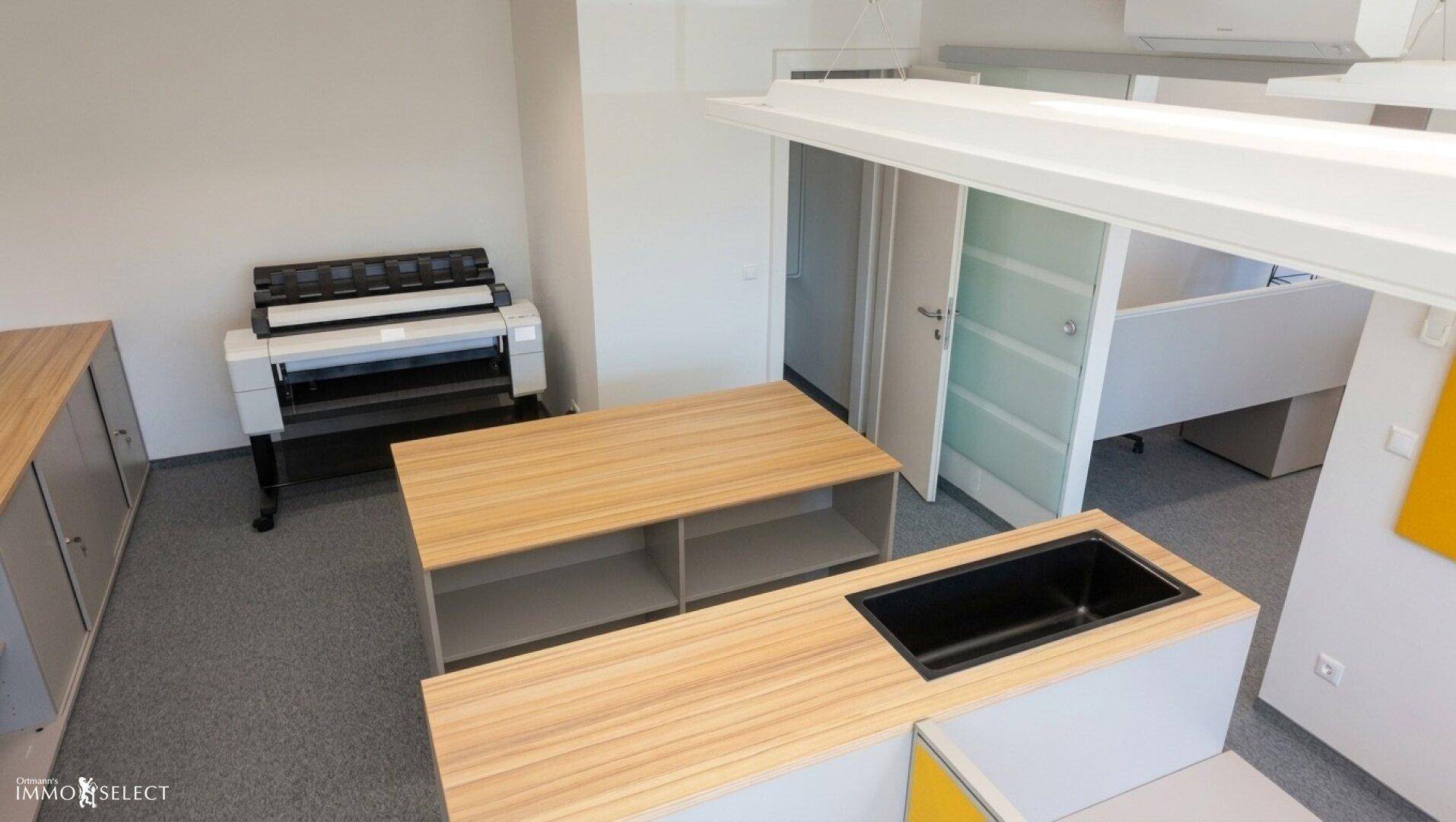 Moderner Bürobereich mit integrierter Spüle, Ablageflächen und Druckerstation.