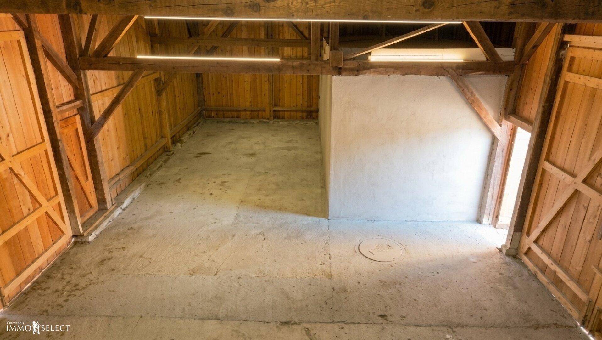 Leerer Lagerraum mit Holzbalken, Holzwänden und Betonboden.